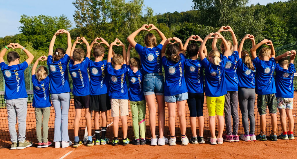 Kinder mit Vereinstrikot auf dem Tennisplatz