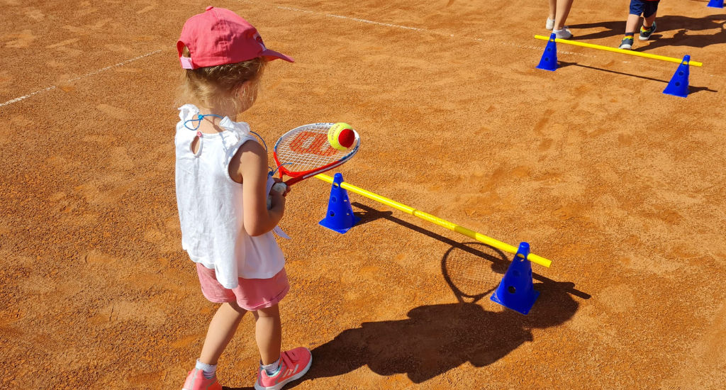 Kind balanciert Ball auf Tennisschläger
