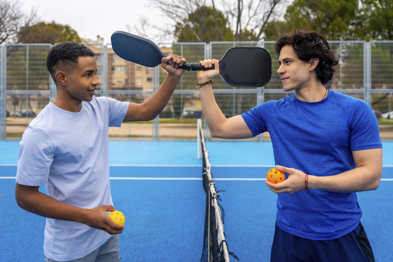 Pickleballspieler am Netz mit Schlägern und Bällen