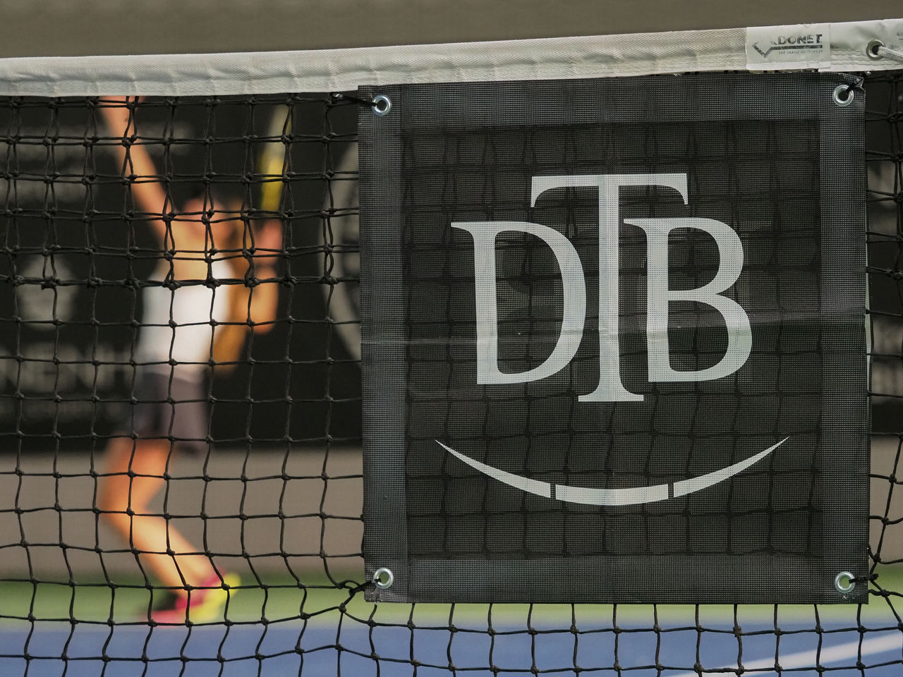 DTB-Branding im Tennisnetz bei den Deutschen Meisterschaften 2021. Im Hintergrund schlägt Alexandra Vecic auf. Fotograf Jürgen Pichler