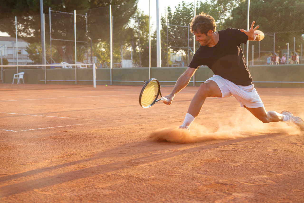 Professional tennis player man playing on court in afternoon.