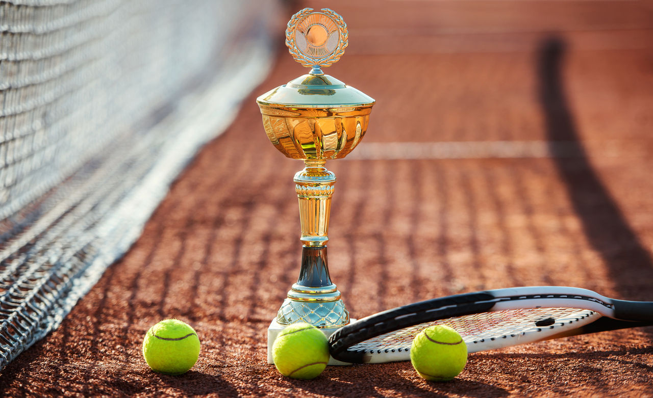 Tennis game. Tennis balls with a racket and cup on the tennis court. Sport, recreation concept