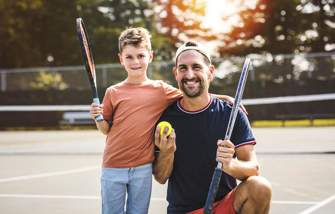 A Father and son play tennis on a summer day