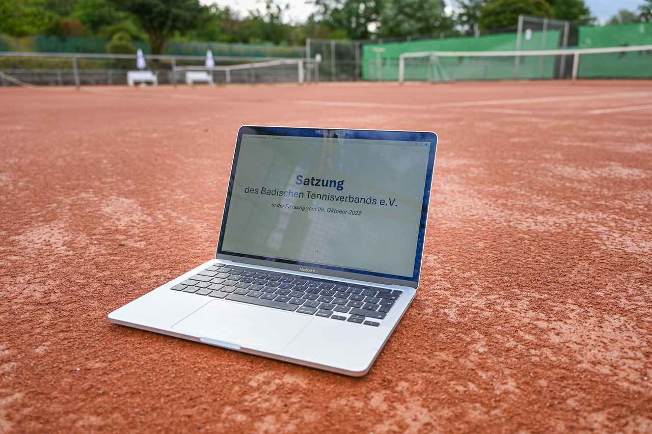 Laptop mit geöffneter Satzung auf Tennisplatz