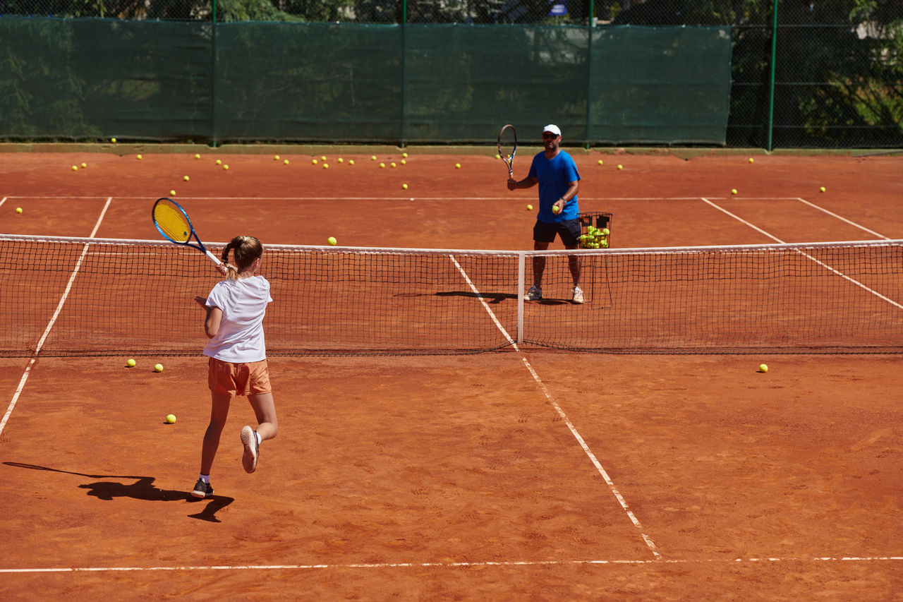 A professional tennis player and her coach training on a sunny day at the tennis court. Training and preparation of a professional tennis player.