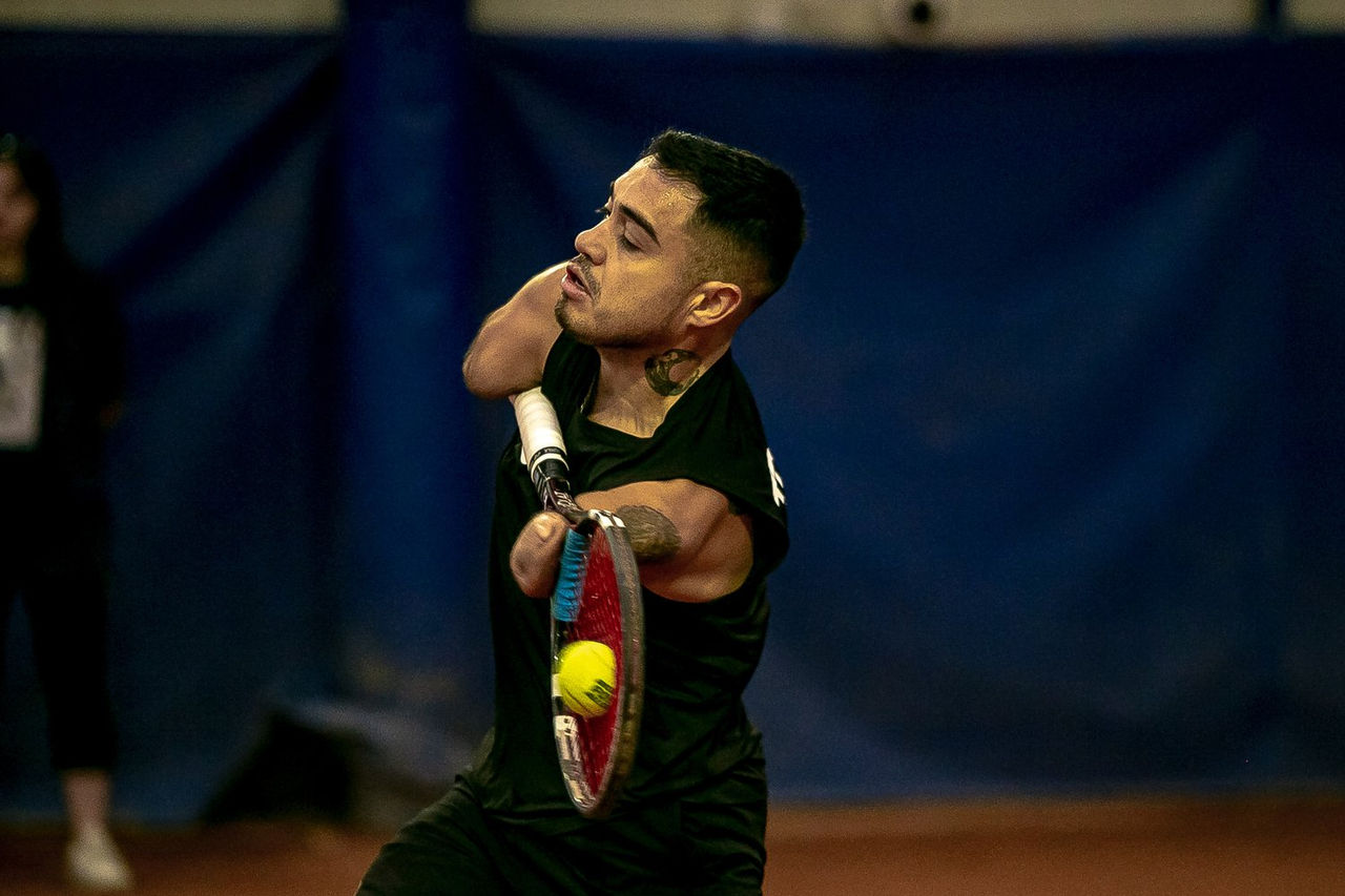 Tennis player mid-swing on indoor court