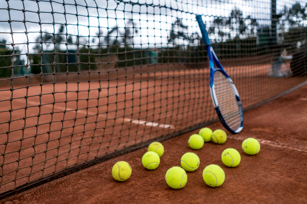 Tennisschläger und Tennisbälle vor einem Tennisnetz