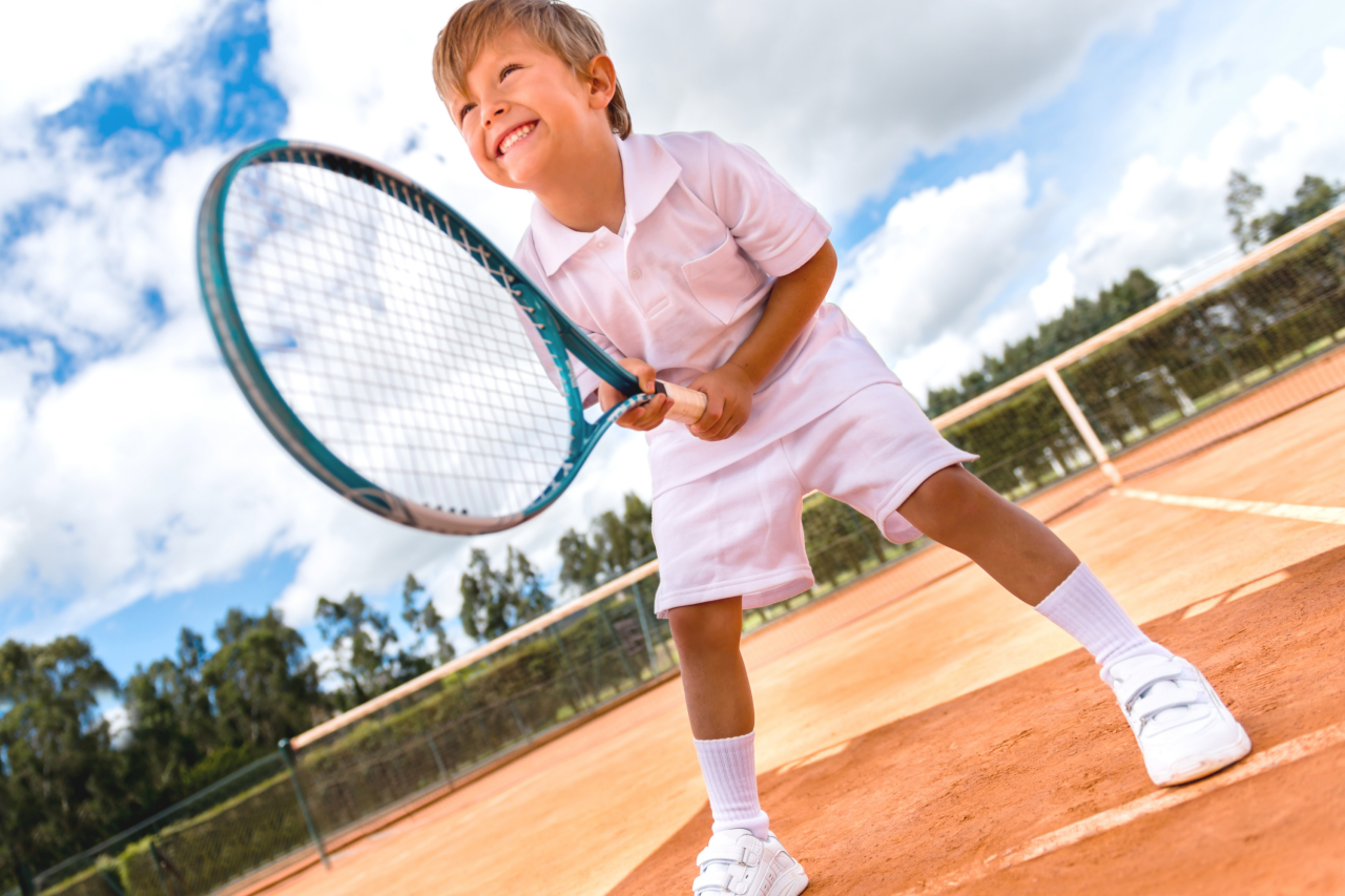 Kind auf Tennisplatz mit Tennisschläger in der Hand
