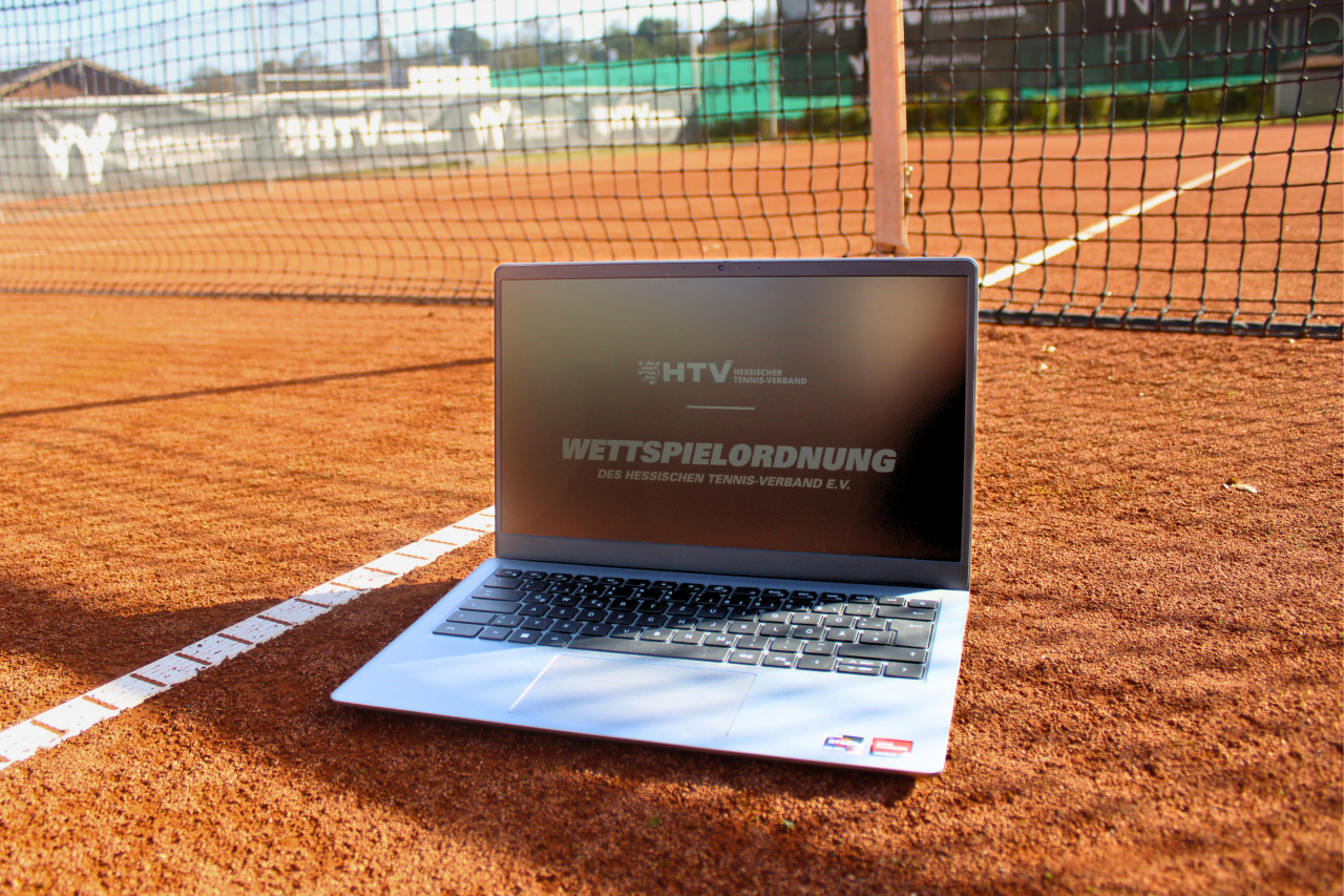 Laptop mit dem Titelbild "Wettspielordnung" auf einem Tennisplatz