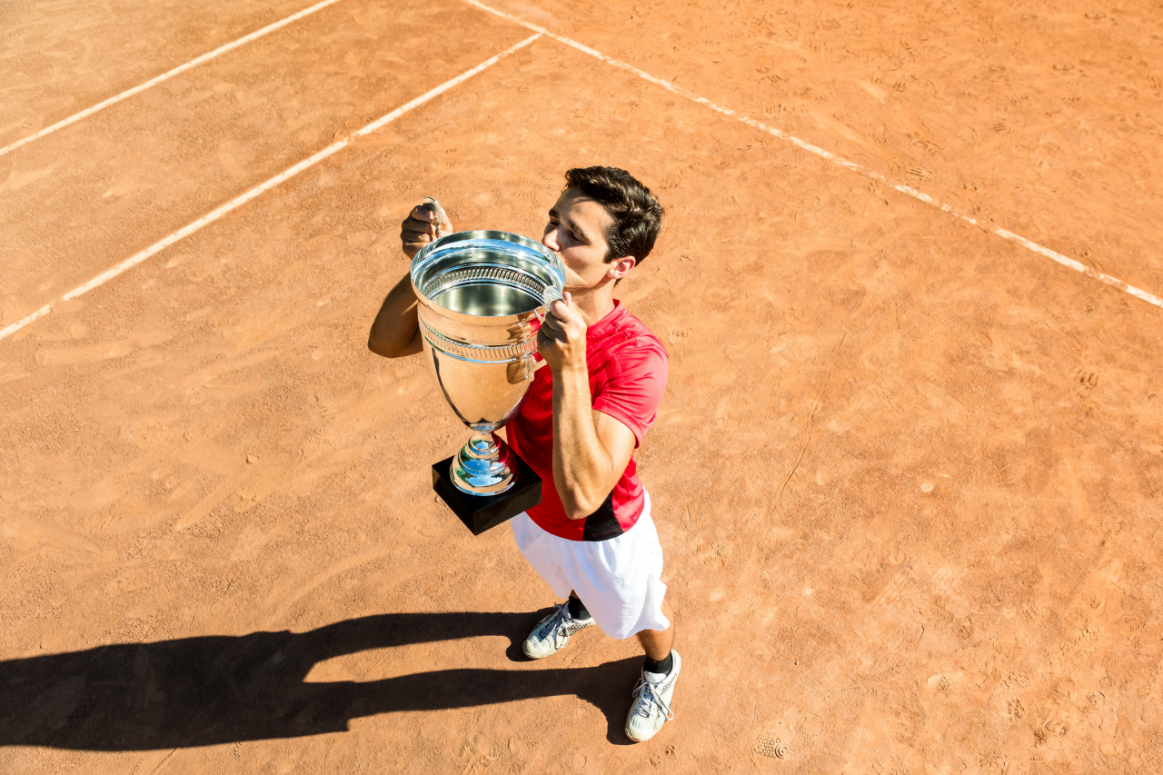 Mann hievt Pokal in die Luft und küsst ihn.