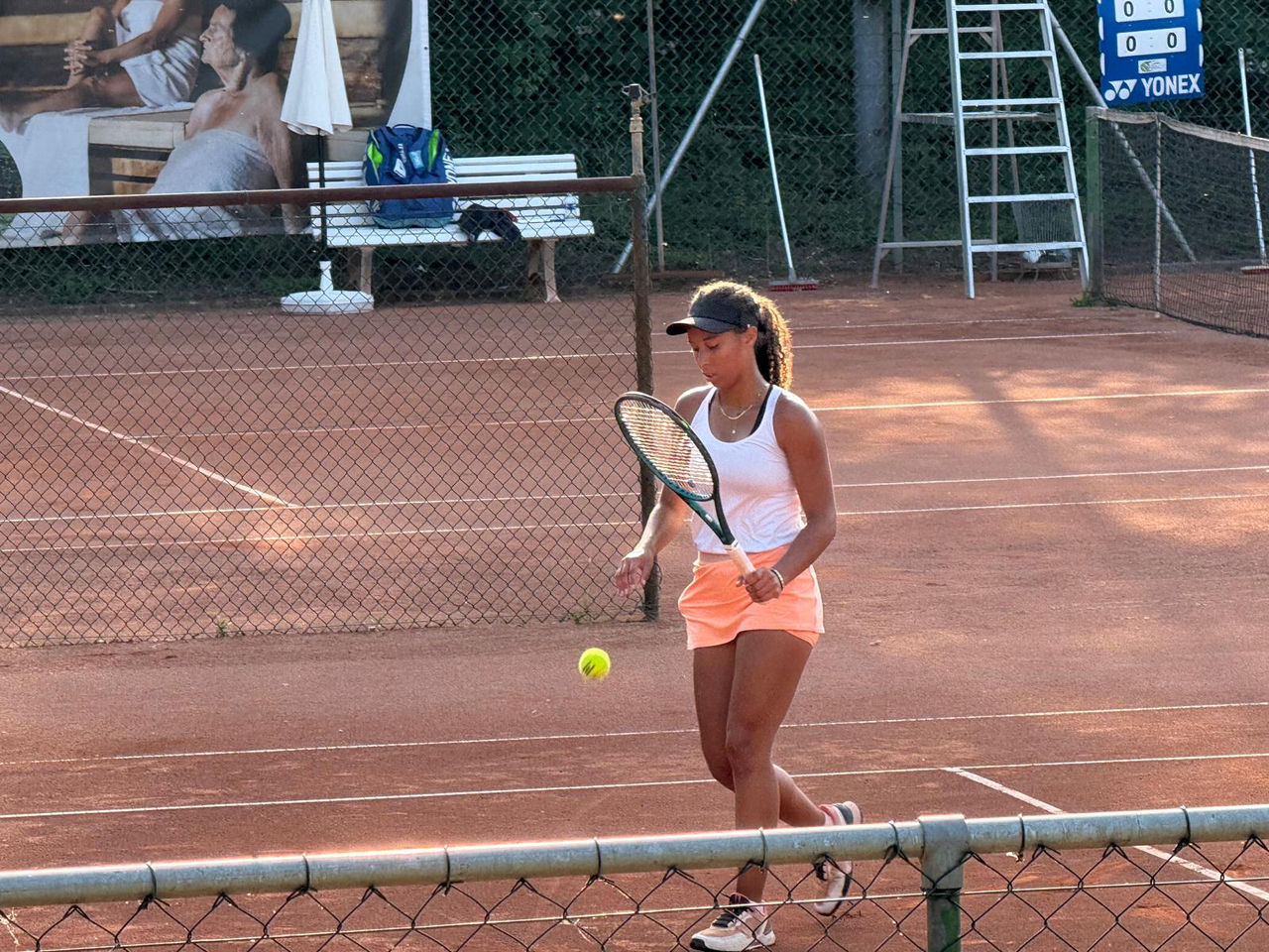 Tennisspielerin prellt mit dem Ball auf dem Sandplatz
