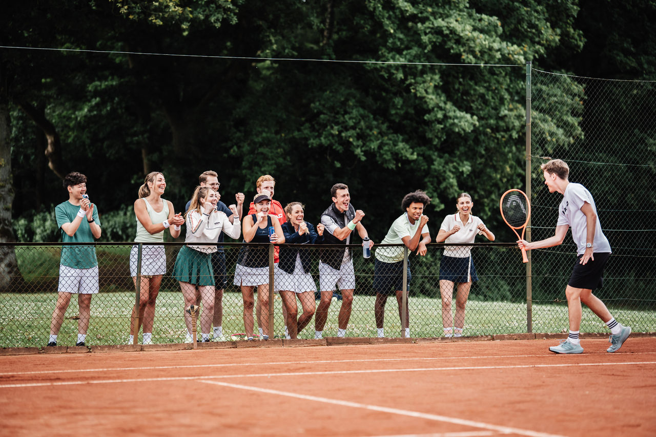 Tennisteam jubelt mit ihrem Spieler auf dem Platz