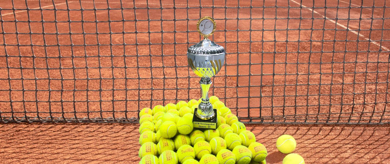 Pokal auf dem Tennisplatz vor dem Tennisnetz.