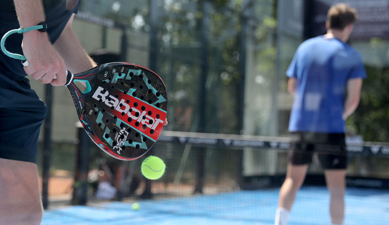 Padelspieler beim Aufschlag. Partner in Position am Netz