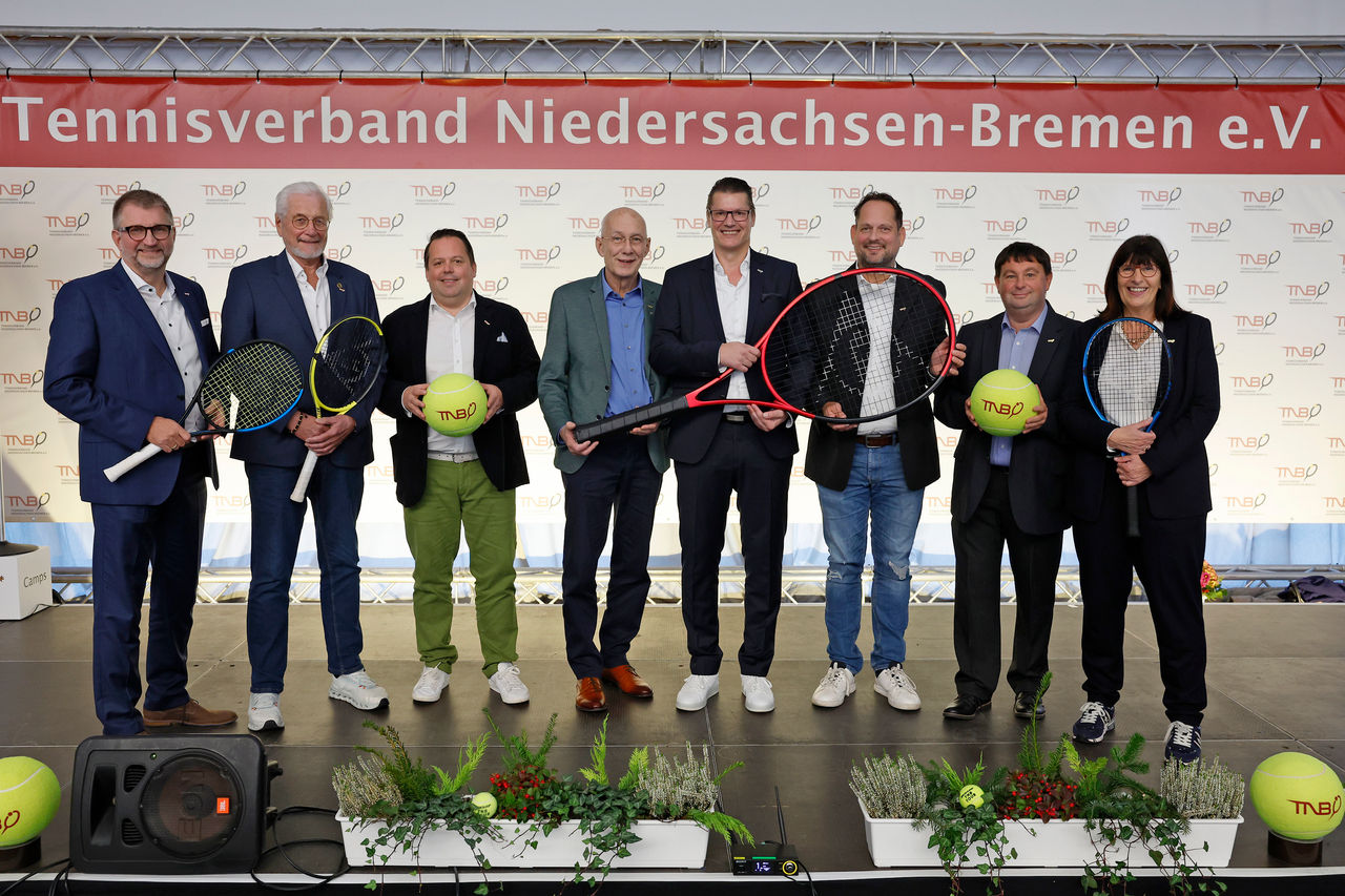 Gruppenbild aller Präsidiumsmitglieder vor TNB Banner auf Bühne