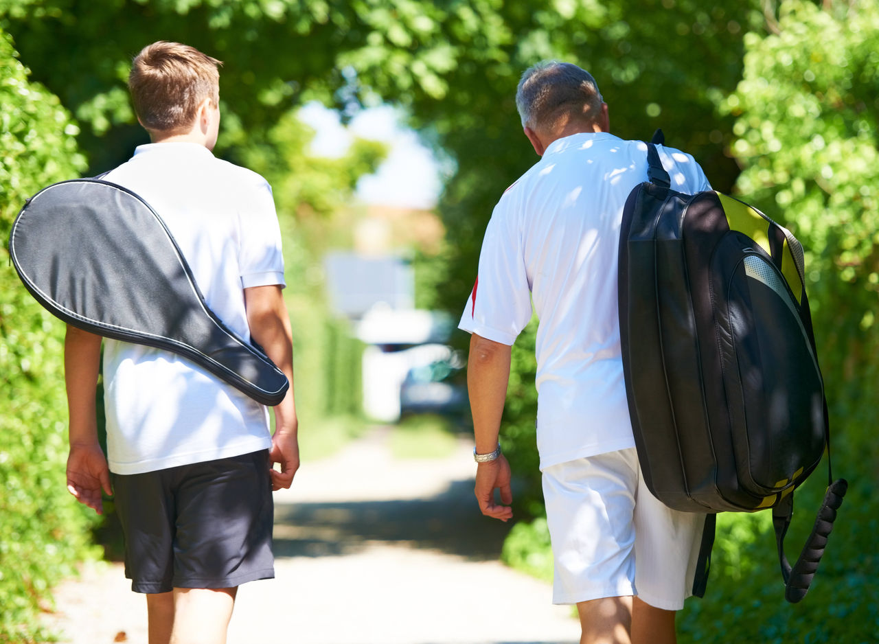 Walking, man or mature father in tennis training, exercise or game with a bag or racket outdoors. Back view, start or healthy dad with son, athlete or person for sports, wellness or fitness workout. model released / property released Copyright: xx